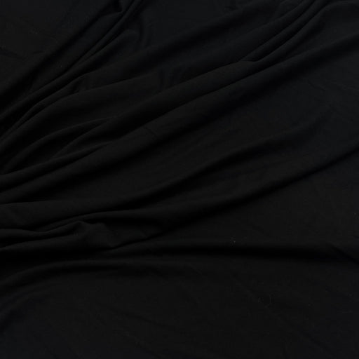 A close-up of draped black fabric with soft folds and a smooth texture.