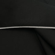 A close-up of black fabric with a thin, braided silver cord or trim running horizontally across the center.