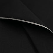 A close-up of black fabric with a folded edge showing a thin silver-gray stitched trim.