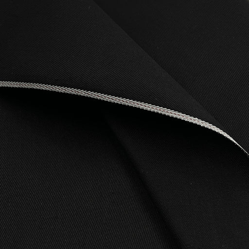 A close-up of black fabric with a folded edge showing a thin silver-gray stitched trim.