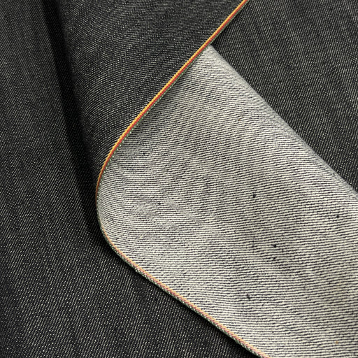 Close up of edge of selvedge denim contrasting the face against the reverse of the fabric