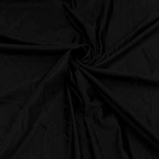 Black fabric draped in a spiral pattern, showing its smooth texture and soft folds.