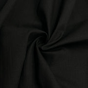 A close-up of draped black fabric with a central swirl, showing the material's fine texture and soft folds.