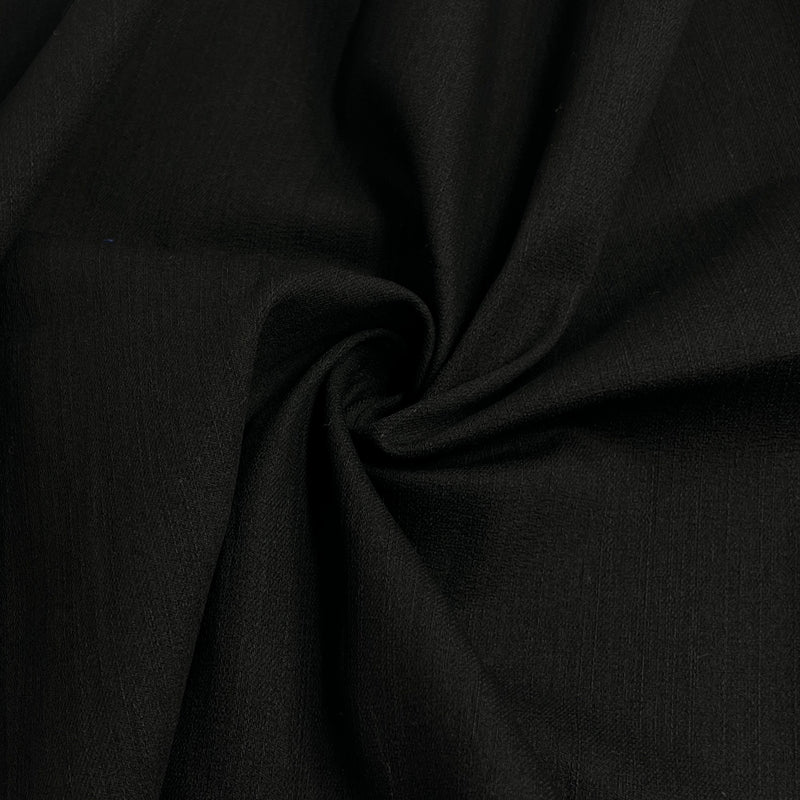 A close-up of draped black fabric with a central swirl, showing the material's fine texture and soft folds.
