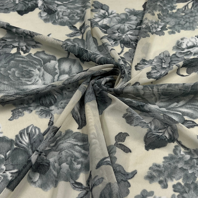A close-up of sheer floral fabric draped in a spiral, showing a gray and black floral print on a warm cream background.