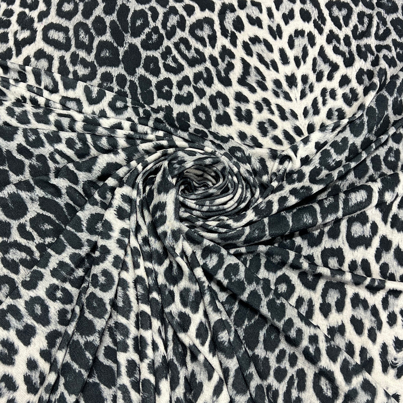 Black and white leopard print fabric draped in a spiral pattern to show its texture and drape.