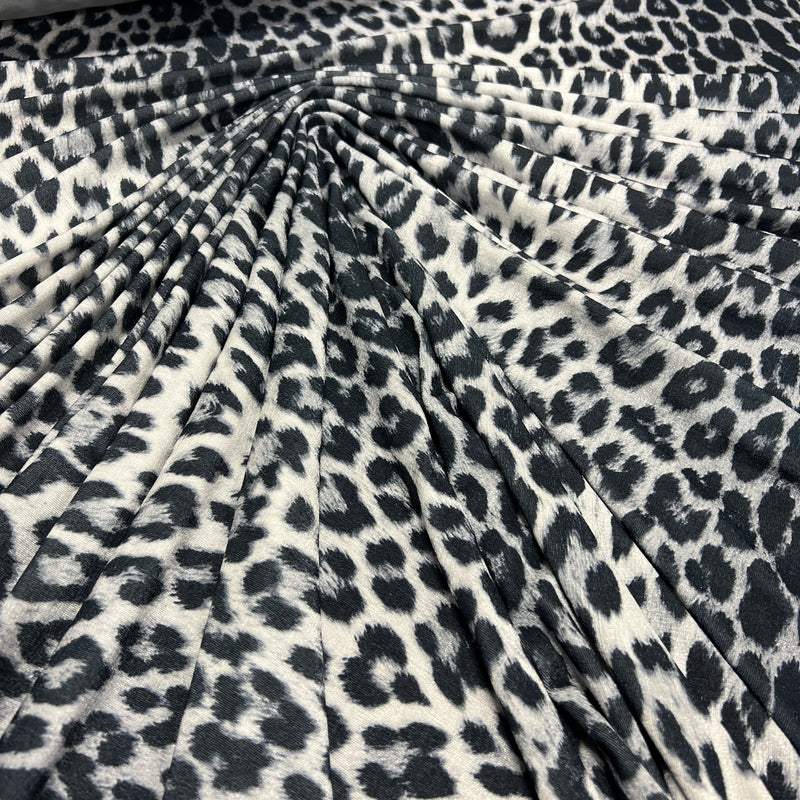 Leopard print fabric draped in a radial pattern, showing a black and off-white animal spot design.