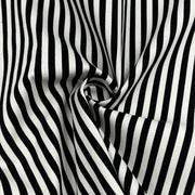 Black and white vertically striped fabric with a soft draped swirl in the center, showing a smooth woven texture.