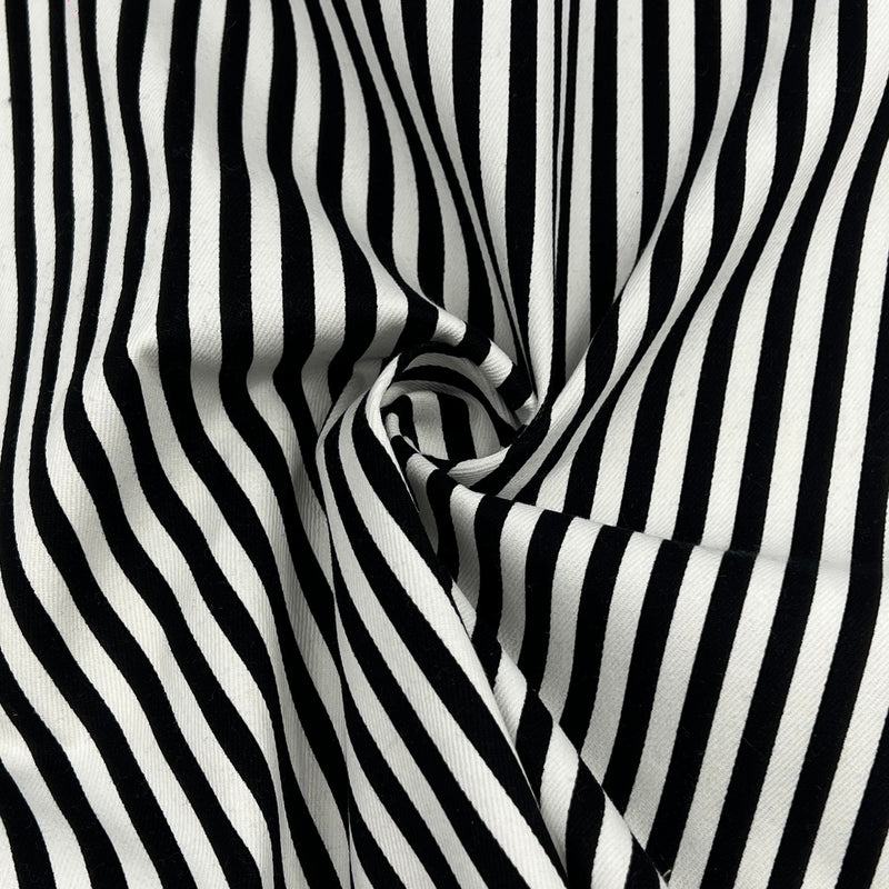 Black and white vertically striped fabric with a soft draped swirl in the center, showing a smooth woven texture.