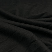 A close-up of draped black wool fabric with soft folds and a matte texture.
