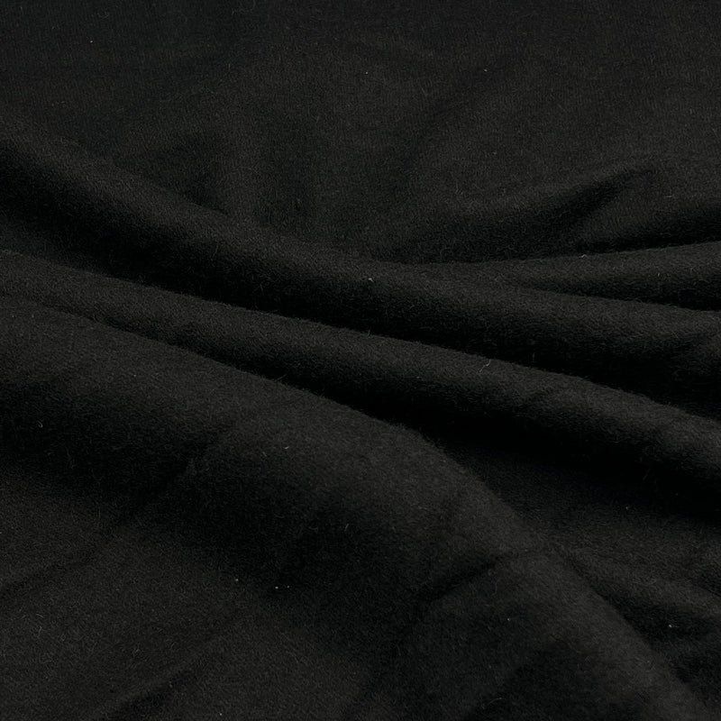 A close-up of draped black wool fabric with soft folds and a matte texture.