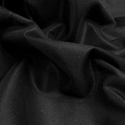 A close-up of draped black fabric with a fine textured weave, showing soft folds and shadows.