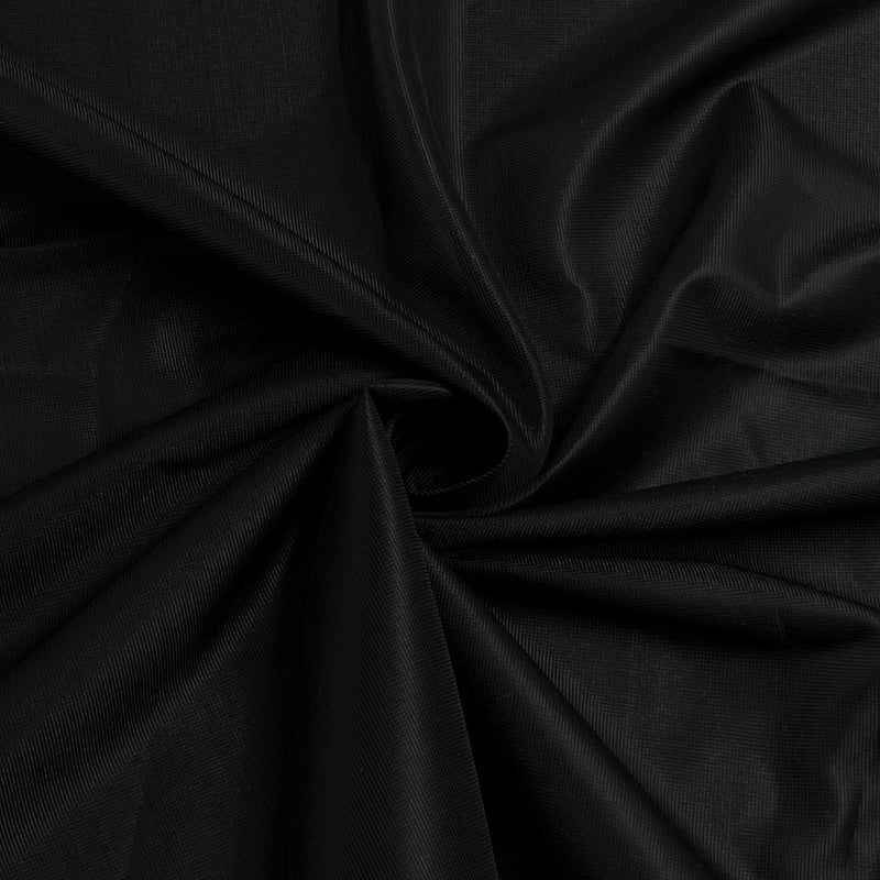 A close-up of draped black fabric with a subtle sheen, arranged in soft folds and swirls.
