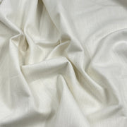 A close-up of draped off-white fabric with a subtle woven texture and soft folds.