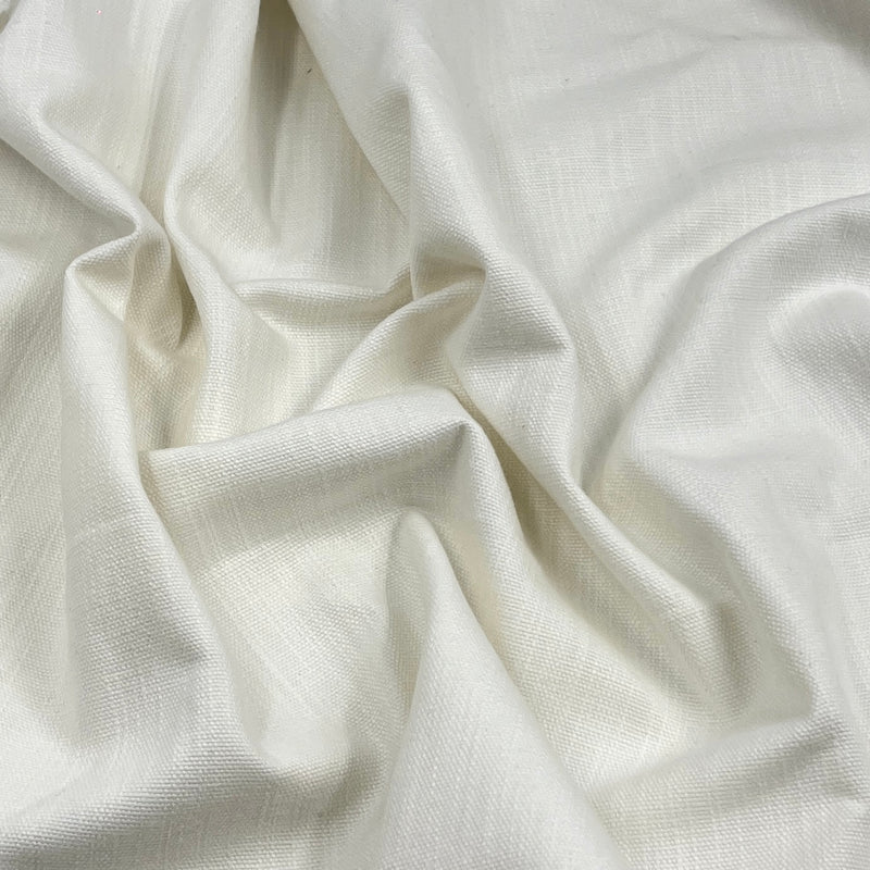 A close-up of draped off-white fabric with a subtle woven texture and soft folds.