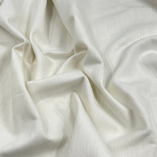 A close-up of draped off-white fabric with a subtle woven texture and soft folds.