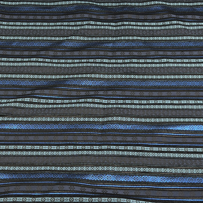 A close-up of a patterned fabric with horizontal stripes in shades of blue, black, and light gray, featuring geometric and tribal-inspired woven motifs.