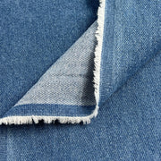 Closeup of blue washed denim showing selvedge folded over face and reverse