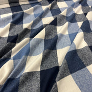 A close-up of draped fabric with a blue, gray, and off-white gingham check pattern.
