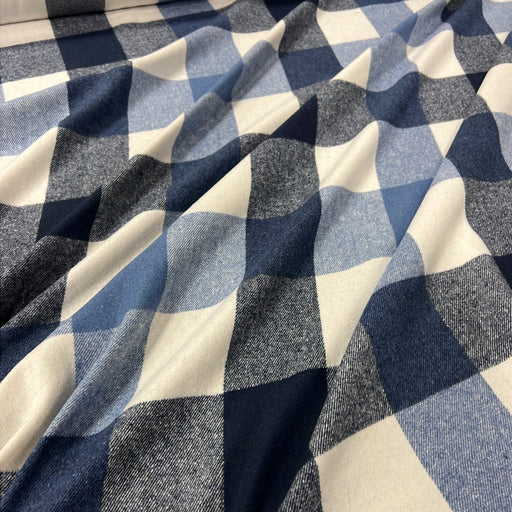 A close-up of draped fabric with a blue, gray, and off-white gingham check pattern.