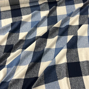 A close-up of draped fabric with a buffalo check plaid pattern in navy blue, medium blue, and cream.