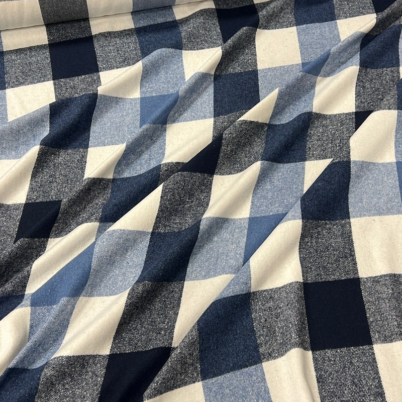 A close-up of draped fabric with a buffalo check plaid pattern in navy blue, medium blue, and cream.