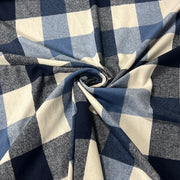 A close-up of a buffalo check fabric with a navy blue, medium blue, and cream plaid pattern, styled in a central swirl to show its texture and drape.