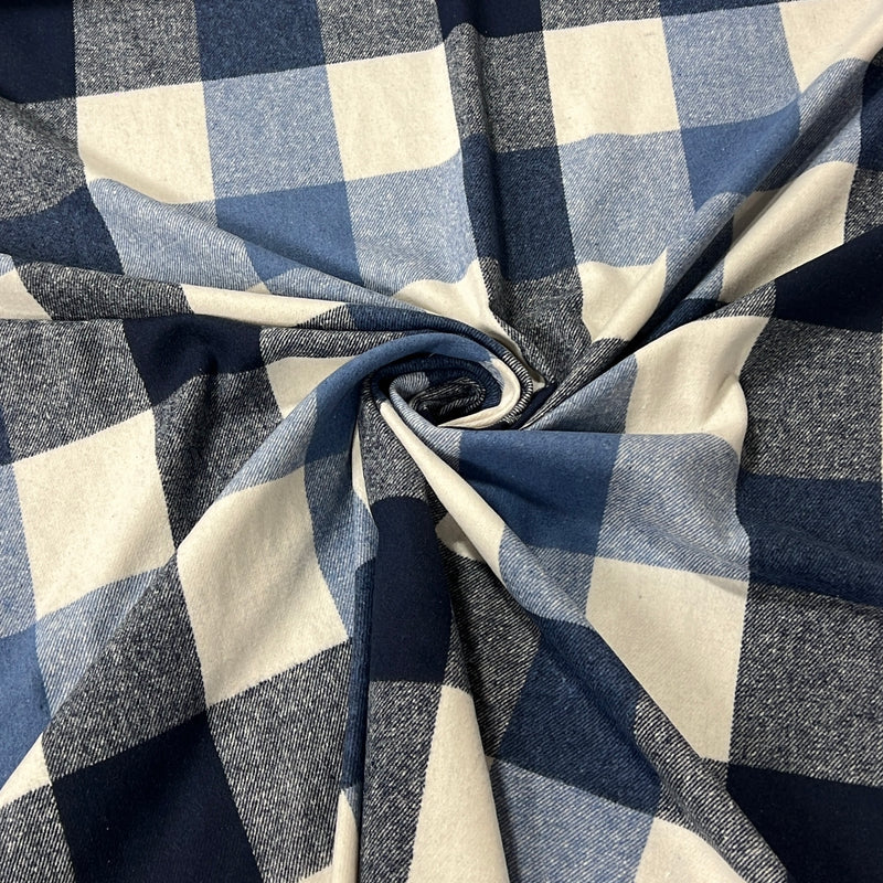 A close-up of a buffalo check fabric with a navy blue, medium blue, and cream plaid pattern, styled in a central swirl to show its texture and drape.