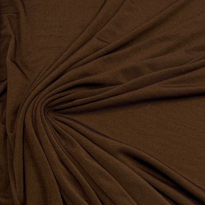 A close-up of draped brown fabric with a gathered swirl pattern, showing the material's texture and color.