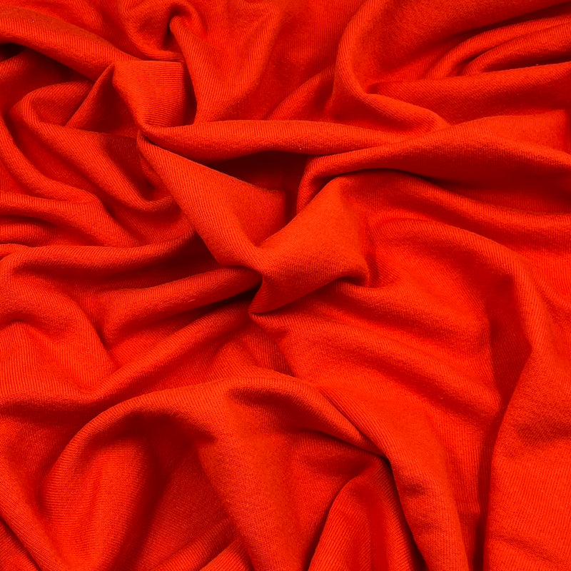 Bright orange draped fabric with soft folds and a smooth texture filling the frame.