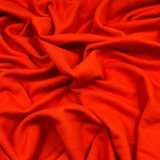 Bright orange draped fabric with soft folds and a smooth texture filling the frame.