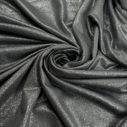 A close-up of draped metallic fabric in a dark charcoal gray color with a subtle shimmering finish, arranged in a spiral pattern.