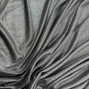 A close-up of draped metallic fabric with a shimmering silver-gray finish and soft folds.