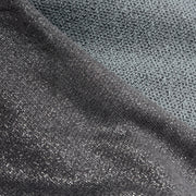 Close-up of a dark gray textured fabric with a subtle metallic sheen, showing a diagonal fold that highlights its knit surface and looped reverse.
