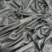 A close-up of draped metallic gray fabric with a subtle shimmer and soft folds filling the frame.
