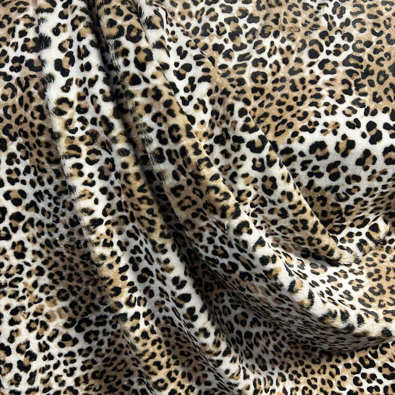 Leopard print fabric with a soft plush texture, draped in elegant folds showing its texture and pattern details.