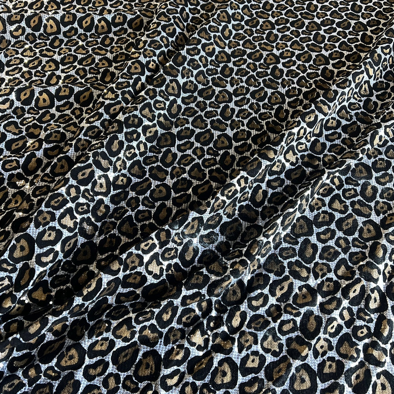 Leopard print fabric with black, brown, and beige spots on a white background, shown with soft folds.
