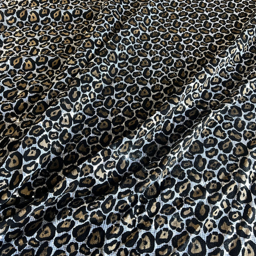 Leopard print fabric with black, brown, and beige spots on a white background, shown with soft folds.