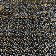 Leopard print fabric with black, brown, and beige spots on a white background, shown as a close-up texture.