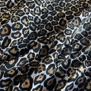 Leopard print fabric with black, brown, and gold spots on a white base, shown in soft folds.