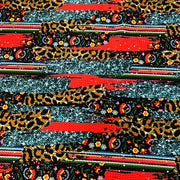 A close-up of a highly textured fabric featuring a complex multicolor pattern with leopard print, glittery silver stripes, red brushstrokes, and small floral motifs.