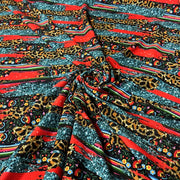 A close-up of a draped fabric with a complex multicolor pattern featuring leopard print, red stripes, and small floral motifs.