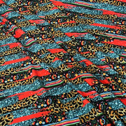 A close-up of a multicolor patterned fabric featuring leopard print, red stripes, and glittery teal sections.