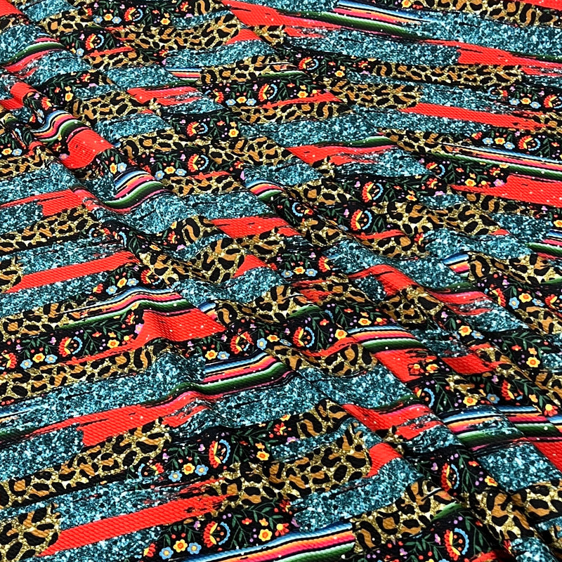 A close-up of a multicolor patterned fabric featuring leopard print, red stripes, and glittery teal sections.