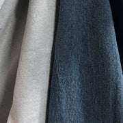 Close-up of two fabric swatches side by side, one in light beige and one in dark slate blue, showing textured material details.