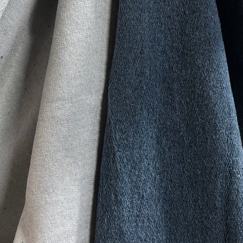 Close-up of two fabric swatches side by side, one in light beige and one in dark slate blue, showing textured material details.