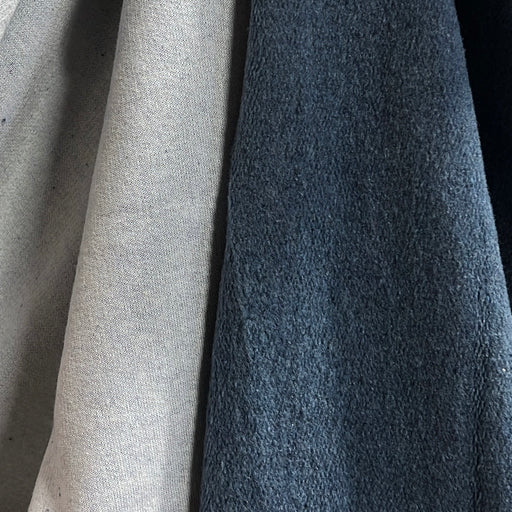 Close-up of two fabric swatches side by side, one in light beige and one in dark slate blue, showing textured material details.