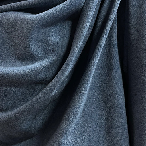 A close-up of draped dark slate blue fabric with a soft, slightly textured surface.