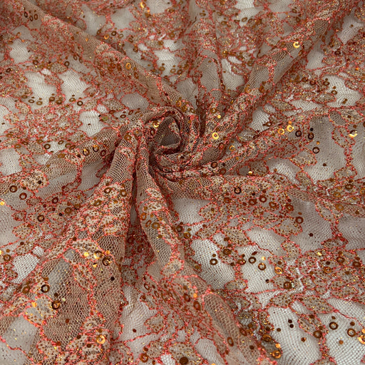 Rose gold sequin lace fabric draped in a spiral pattern, showing intricate floral lace details covered in shimmering rose gold sequins and glitter.