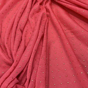 A close-up of draped dusty rose pink fabric with small metallic silver rhinestone dots scattered across it.